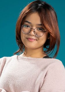 Young woman with shoulder-length hair and glasses smiling confidently