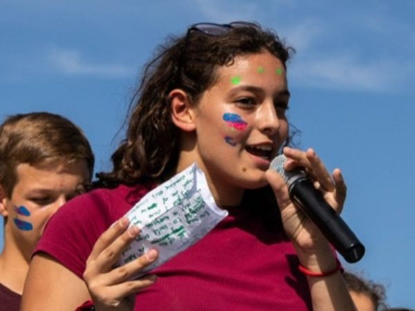 A young woman with face paint speaks into a microphone