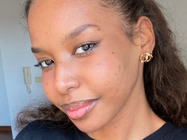 Headshot of a smiling woman with wavy hair and gold hoop earrings