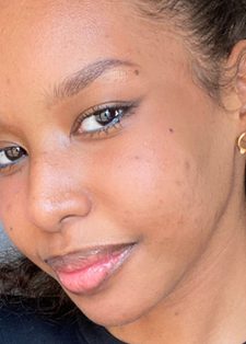 Headshot of a smiling woman with wavy hair and gold hoop earrings