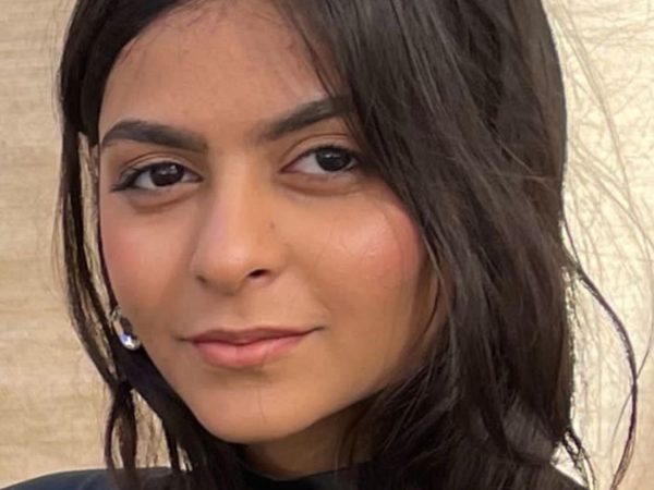Headshot of a woman with long, dark hair and a subtle smile set against a neutral background