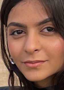 Headshot of a woman with long, dark hair and a subtle smile set against a neutral background