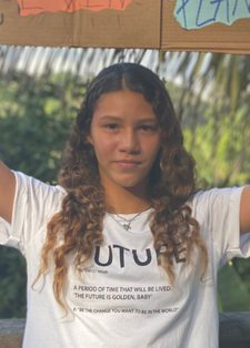 A young woman stands outside, holding a handmade cardboard sign with colourful drawings
