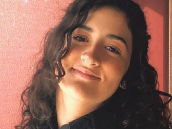 Headshot of a young woman with long, curly dark hair smiling softly