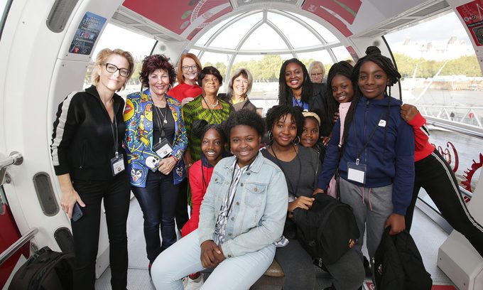 A diverse group of smiling people inside a large observation wheel pod.