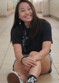 Smiling woman sitting on a tiled corridor floor