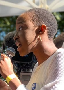 A person speaks passionately into a microphone at an outdoor event