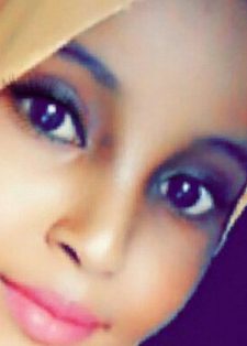 A person wearing a peach-coloured headscarf smiles softly.