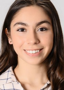 Headshot of Selin Özünaldım smiling in the camera. She has long brown hair and is wearing a cream and blue check top.