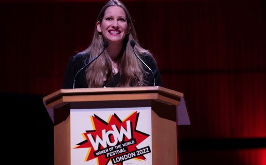 The author Laura Bates stands at a lectern at the WOW Festival