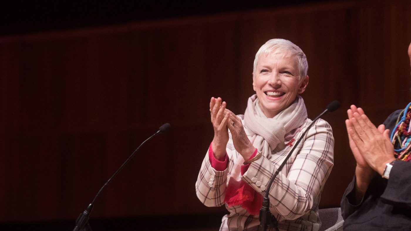 Two women sit on stage clapping