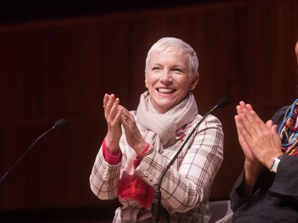 Two women sit on stage clapping