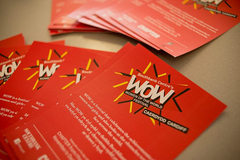 A collection of bright red flyers laid out on a table. The flyers are titled "Southbank Centre's Women of the world festival - Caerdydd, Cardiff"