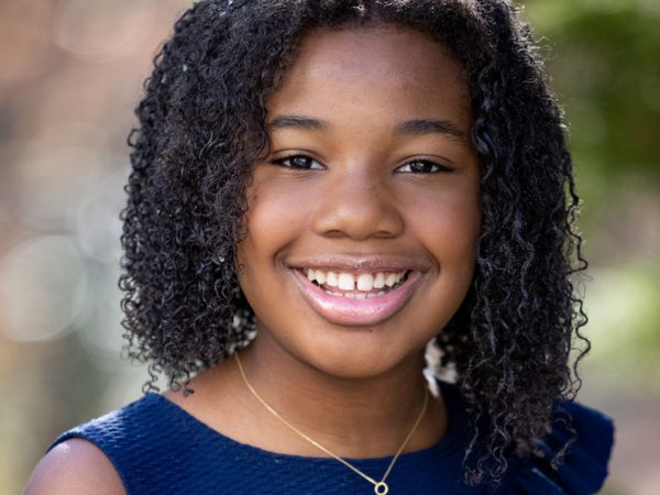 Yolanda Renee King smiles at the camera. She has dark, shoulder length curly hair and is wearing a blue top and necklace.