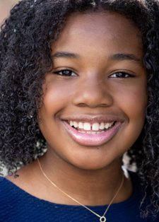 Yolanda Renee King smiles at the camera. She has dark, shoulder length curly hair and is wearing a blue top and necklace.